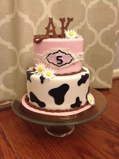 a three tiered cake decorated with pink, black and white cow print icing