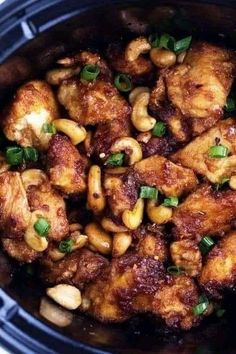 chicken and cashews in a slow cooker with garnishes on top