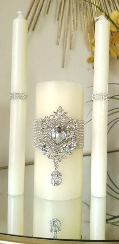 a white candle sitting on top of a table next to two candles with rings around it