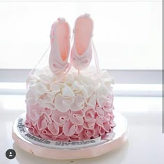 a pink and white cake decorated with ballet shoes