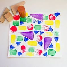 a child's art project with colored shapes and wooden pegs on the table