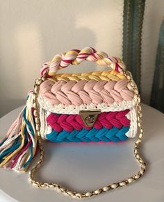 a multicolored handbag sitting on top of a white table next to a cactus