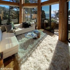 a living room with large windows and a white rug on the floor in front of it