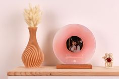 a wooden shelf with a vase and photo frame on it next to a small teddy bear