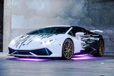 a white sports car with black and white stripes on it's body parked in front of a building