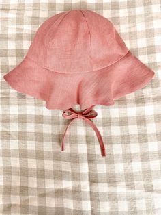 a pink hat is tied up on a checkered bed sheet with a knot at the end