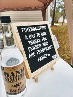 a bottle of alcohol sitting on top of a table next to a sign that says, friends giving a day to one thanks for friends who are practically