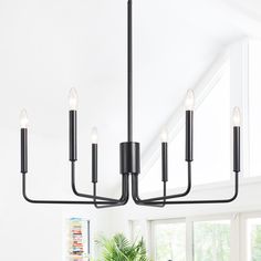 a black chandelier hanging from the ceiling in a room with white walls and windows