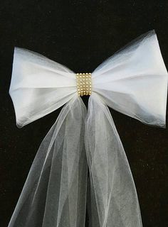 a white bow with pearls on it is tied to a black background and sits atop a veil