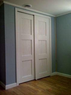 an empty room with two doors and hard wood flooring