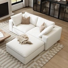 a living room with a large white sectional couch and coffee table in the center area