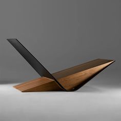 a laptop computer sitting on top of a wooden stand in front of a gray wall