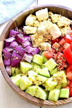 a wooden bowl filled with lots of different types of food on top of a table