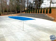 an empty swimming pool in the middle of a concrete patio with steps leading up to it