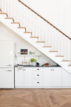 a kitchen with white cabinets and wooden stairs