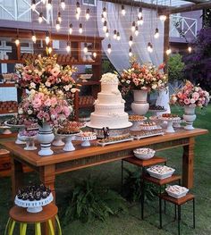 a table topped with lots of cakes and desserts next to tall vases filled with flowers