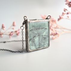 "Keep the nature close to your heart wherever you are. This is a hand painted Queen Anne's Lace flower pendant in a unique green-gray color.  Waste window glass gets a new life as pieces of art to wear. Perfect sustainable gift for someone you care about, that care about the environment. The two lobster clasps make it a thoughtful gift for someone with weakness in hands and arms, it's easy to put on from the front, in addition to just being cool and different. Two functionalities in one item! Wh Green Handmade Necklace For Keepsake, Nature-inspired Hand Painted Necklace For Gift, Hand Painted Nature-inspired Necklace For Gift, Green Necklace With Natural Inclusions For Gift, Green Hand Painted Necklace For Gift, Green Botanical Necklace Perfect For Gifting, Green Botanical Necklace For Gift, Green Botanical Necklace For Gifts, Green Botanical Style Necklace For Gift