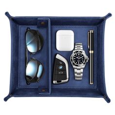 an open black leather case with various items in it including sunglasses, watch and pen