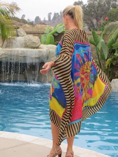 Shine in this stunning sun-print caftan with contrasting, striped border print. The design is a copy of famous American artist, Laurel Burch's   painting "Harmony Under the Sun.   Wear as a dress or cover up at the pool or beach for glamorous resort style.  Soft-flowing fabric with a silk-like feel.  Caftan is made to fit size small to x-large. It is 58 inches wide and 40 inches in length, measured from the shoulder to the center, bottom edge and falls longer at the sides.  The side seams are 7 Striped Kaftan For Summer Beach Cover-up, Multicolor Beachwear Kaftan For Poolside, Bohemian Cover-up With Vibrant Print For Poolside, Bohemian Summer Kaftan With Abstract Print, Bohemian Vibrant Print Poolside Cover-up, Multicolor Tunic Kaftan For Vacation, Bohemian Multicolor Kaftan For Vacation, Multicolor Print Kaftan For The Beach, Bohemian Poolside Cover-up With Vibrant Print