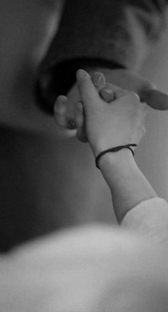 black and white photograph of a person holding the hand of another person's wrist