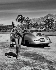 a black and white photo of a woman walking next to a car