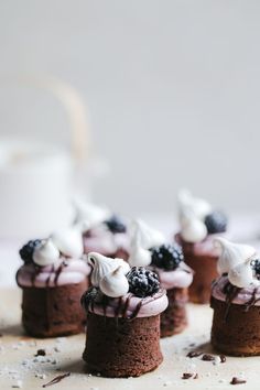 mini chocolate cakes with whipped cream and blackberries on top, sitting on a table