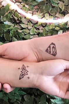 two people with matching tattoos on their arms, one is holding the other's hand