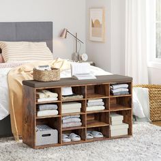 a bed room with a neatly made bed and lots of linens on the floor