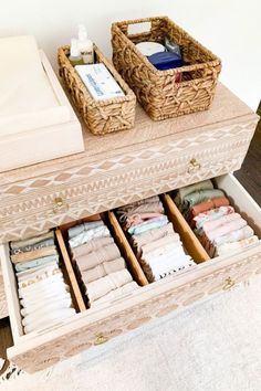 an open drawer with folded clothes in it on top of a wooden table next to a white rug