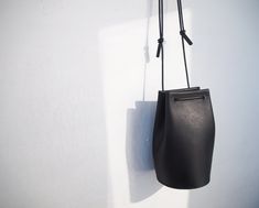 "Classic yet contemporary bucket bag, combined a minimalism and functional. The body made from Italian vegetan leather, using leather cord for the shoulder strap. The shoulder strap is adjustable, able to enjoy this bag for 3 ways as a crossbody bag, one-shoulder bag and handbag. Has a card sized inside pocket. Approximate Dimensions: W 4.75\" x H 8\" x D 4.75\" W 12cm x H 20cm x D 12cm Inside pocket W 3.50\" x H 3.50\" W 9.5cm x H 9.5cm - 100% Vegetable tanned leather (body) - Genuine leather c Minimalist Bucket Bag With Detachable Strap For Office, Minimalist Bucket Bag For Everyday Use, Minimalist Bucket Bag For Everyday, Minimalist Everyday Bucket Bag, Minimalist Crossbody Bucket Bag For Travel, Minimalist Everyday Bucket Bag With Adjustable Strap, Minimalist Soft Leather Bucket Bag For On-the-go, Minimalist Office Bucket Bag With Adjustable Strap, Minimalist Bucket Shoulder Bag With Adjustable Strap