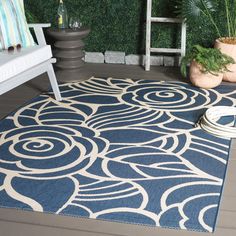 a blue and white area rug on the floor next to a bench with potted plants