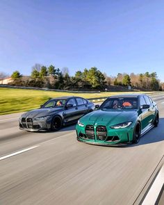 two green cars driving down the road in front of each other on a sunny day