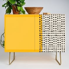 a potted plant sitting on top of a yellow and black cabinet with polka dots