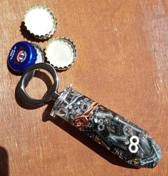 a bottle opener sitting on top of a wooden table next to two empty beer bottles