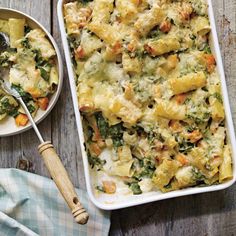 a casserole dish with spinach, cheese and other toppings on a wooden table