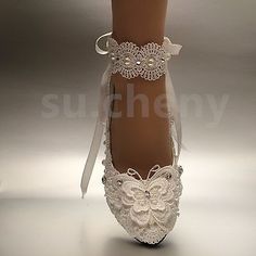 a woman's white wedding shoes with lace and pearls on the heel, decorated with bows