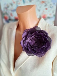 a close up of a purple flower on a mannequin's neck piece