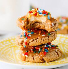 a stack of cookies with frosting and sprinkles on a yellow plate