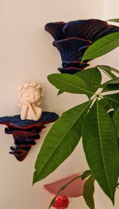 two vases are sitting on the wall next to a green leafy plant in front of them