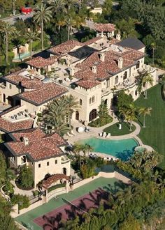 an aerial view of a mansion with pool and trees in the foreground, surrounded by palm trees