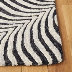 a black and white area rug on the floor with wood floors in the background,