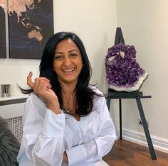 a woman sitting on a couch with her hand up in the air and smiling at the camera