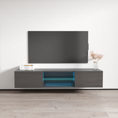 an entertainment center with a large television on it's stand and blue light under the cabinet