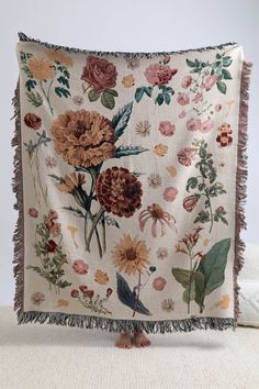 an embroidered pillow with flowers on it and fringes hanging from the front, sitting on a white surface