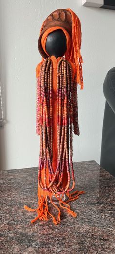 an orange beaded mannequin is sitting on a table