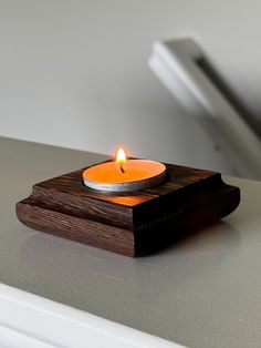 a lit candle sitting on top of a wooden block