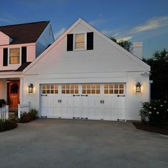 a white house with black shutters on the front and side windows at night time