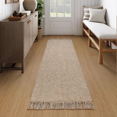 a living room with wood flooring and white walls, along with a rug on the floor