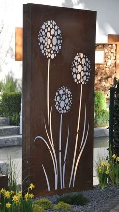 a large metal sculpture with flowers painted on it's sides and grass in the foreground