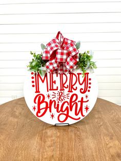 a merry bright sign with a bow on it sitting on top of a wooden table